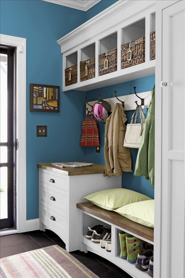 White and blue mud room.  This little mudroom is beutifully made with white and blue color palette, basket storage, big hooks to hang up coats, easy to clean black flooring, bench. A cozy bench allows you to perch while you pull your boots on. Looks so welcoming. 