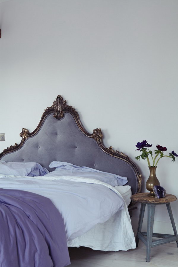 Eye Catching French Headboard: In the master bedroom, a French headboard is reupholstered in a soothing purple gray velvet that blends well with Farrow & Ball Great White painted walls. 